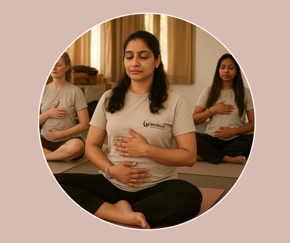 Drei Frauen sitzen im Schneidersitz auf Yogamatten und halten die Hände auf dem Bauch – Achtsamkeitsübung in einem Geburtsvorbereitungskurs.