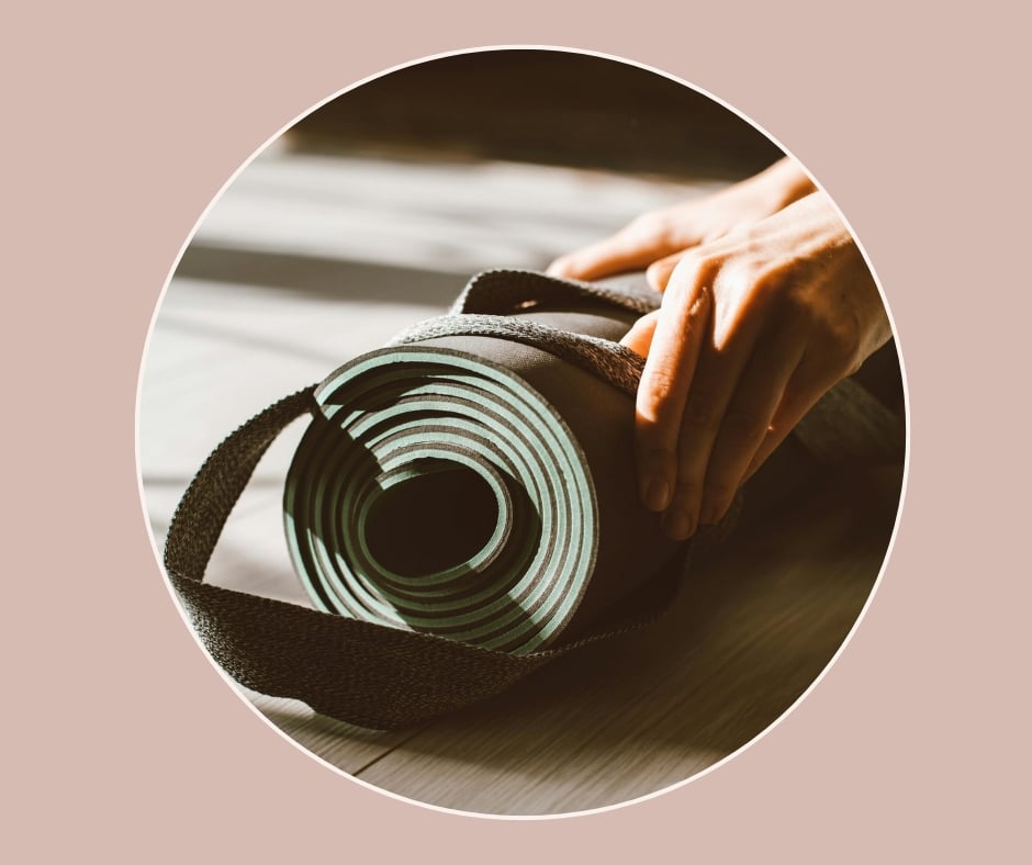 Zusammengerollte Yogamatte wird mit beiden Händen auf dem Boden vorbereitet